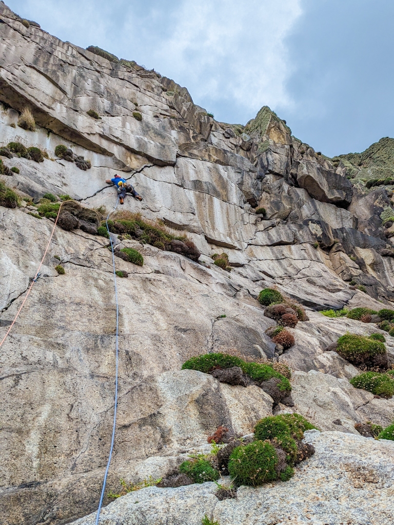 A photo of Jesse half way up a big diagonal crack on a route called Destiny. His legs are out stretched and his right hand is high in the crack.